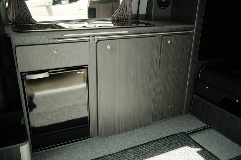 campervan cooking | integrated storage space with small fridge and locking cupboards made of marine plywood