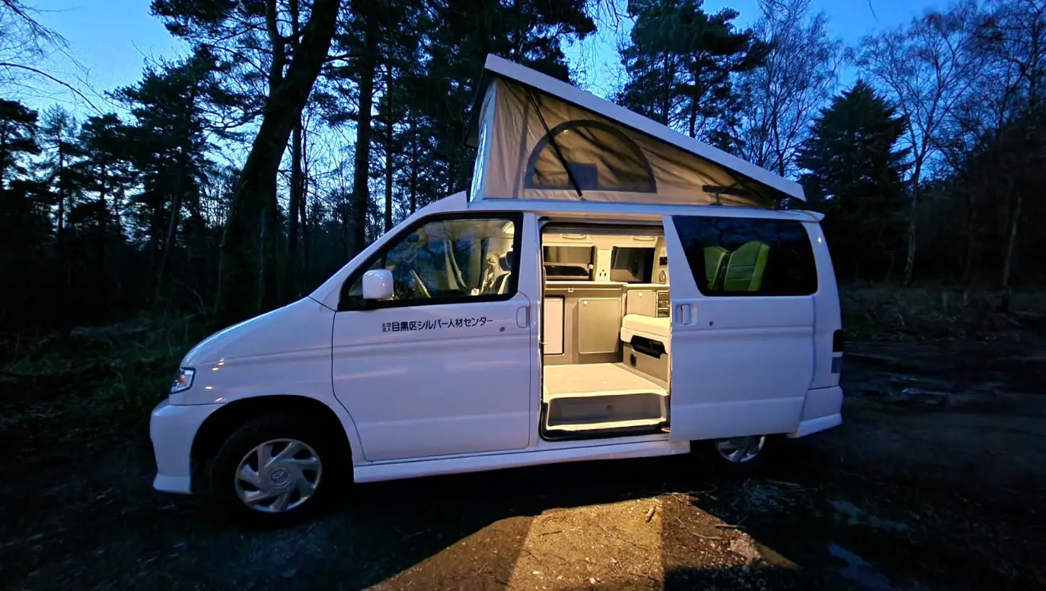 campervan at night with lights on in woodland