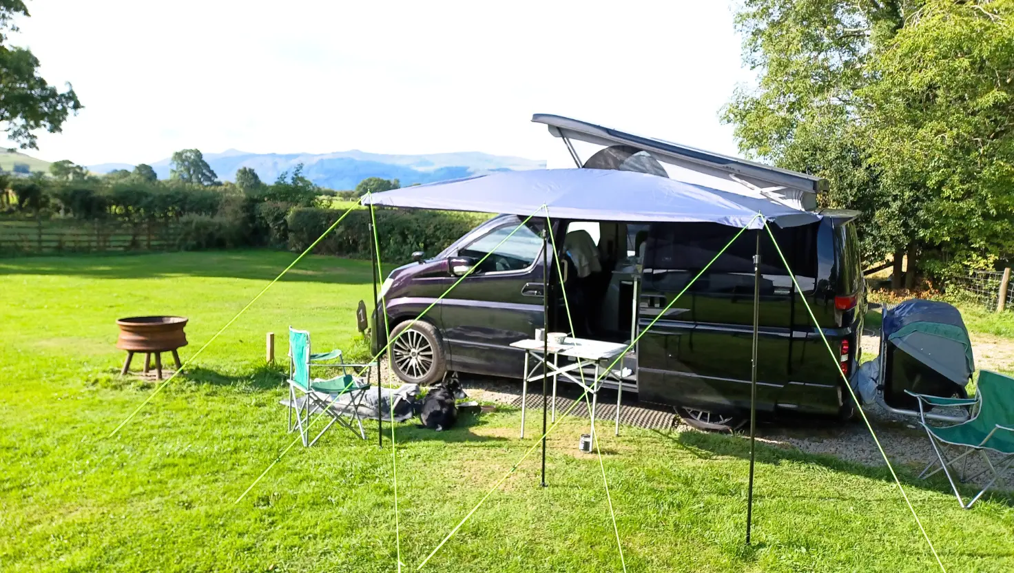 black campervan with an awning, and picnic table, at one of the UK campervan picnic spots