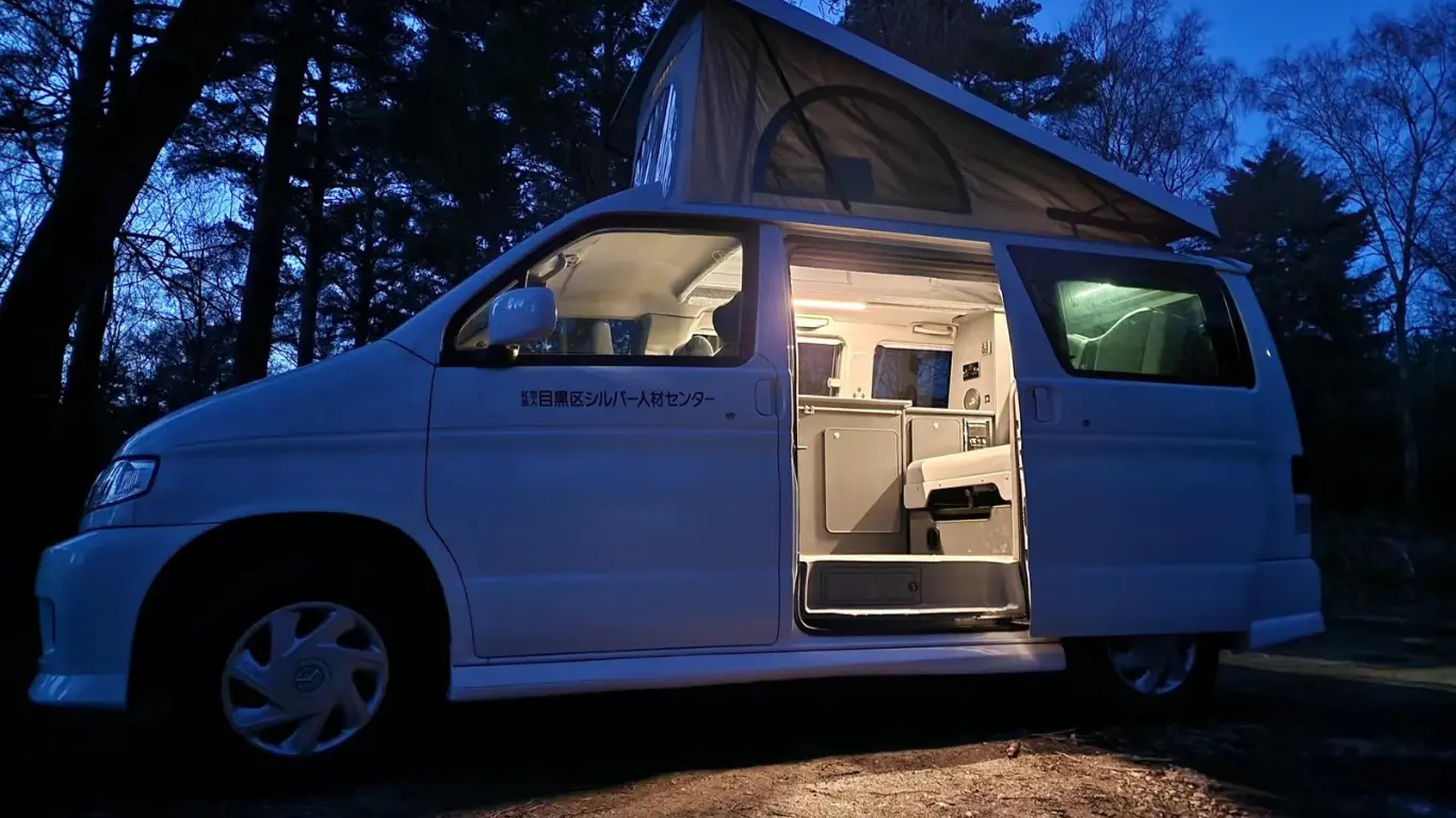 campervan at night in woodland with roof up and side door open