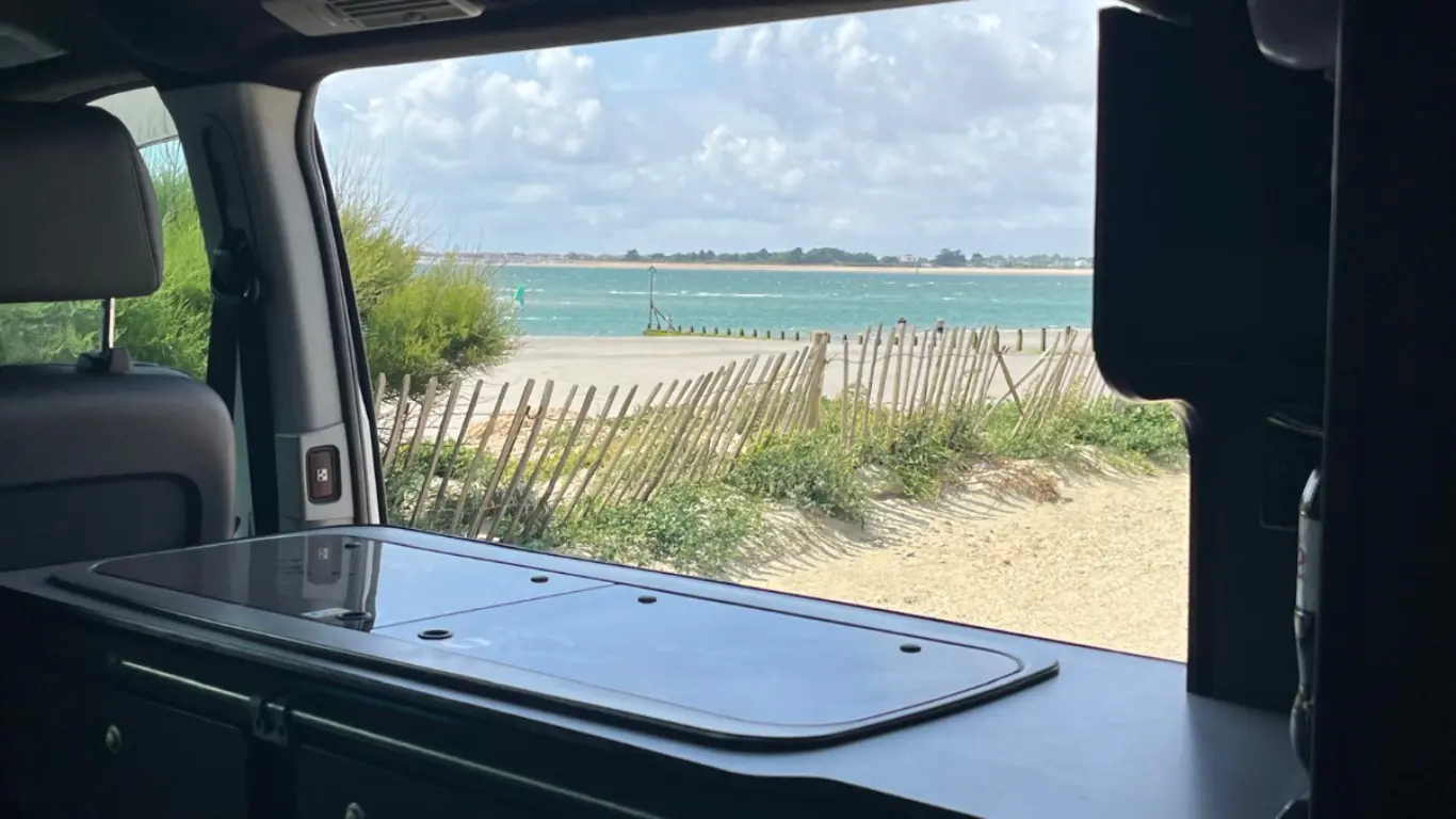 campervan living tips showing the kitchenette cooker with the window open looking at a view of the sea