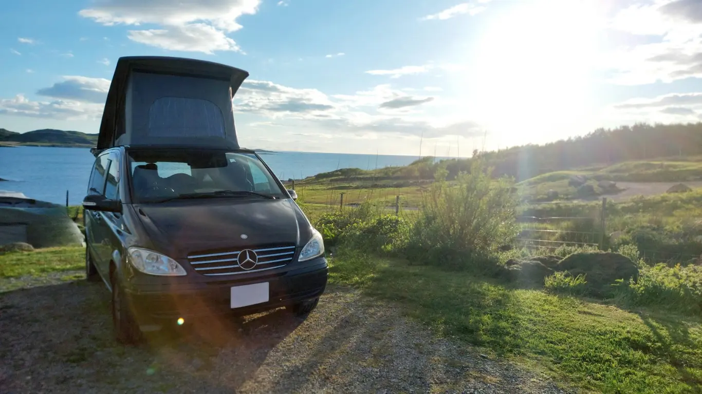 black campervan parked by the coast in the sunshine