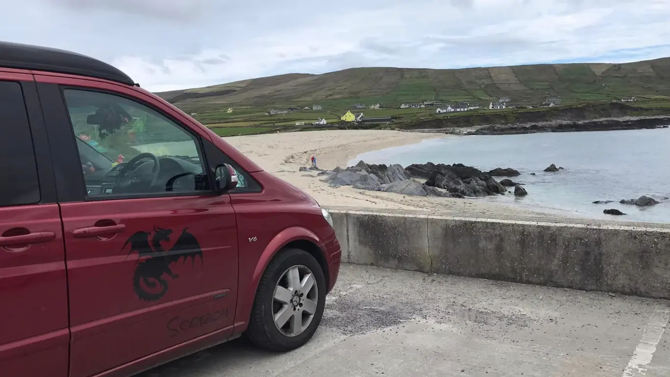Red campervan parked at a beach
